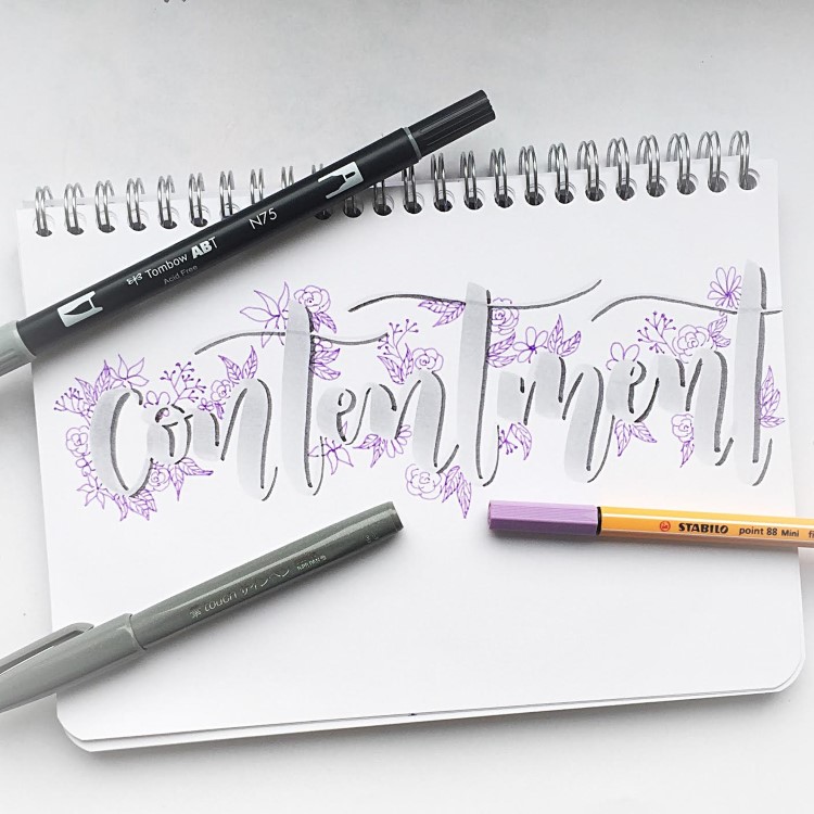 graues Handlettering mit violetten Blümchen - contentment