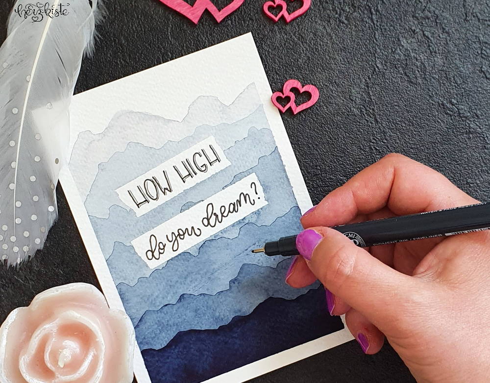Lettering Karte mit einem Hintergrund mit Bergen aus Aquarell und dem Spruch: How high do you dream?